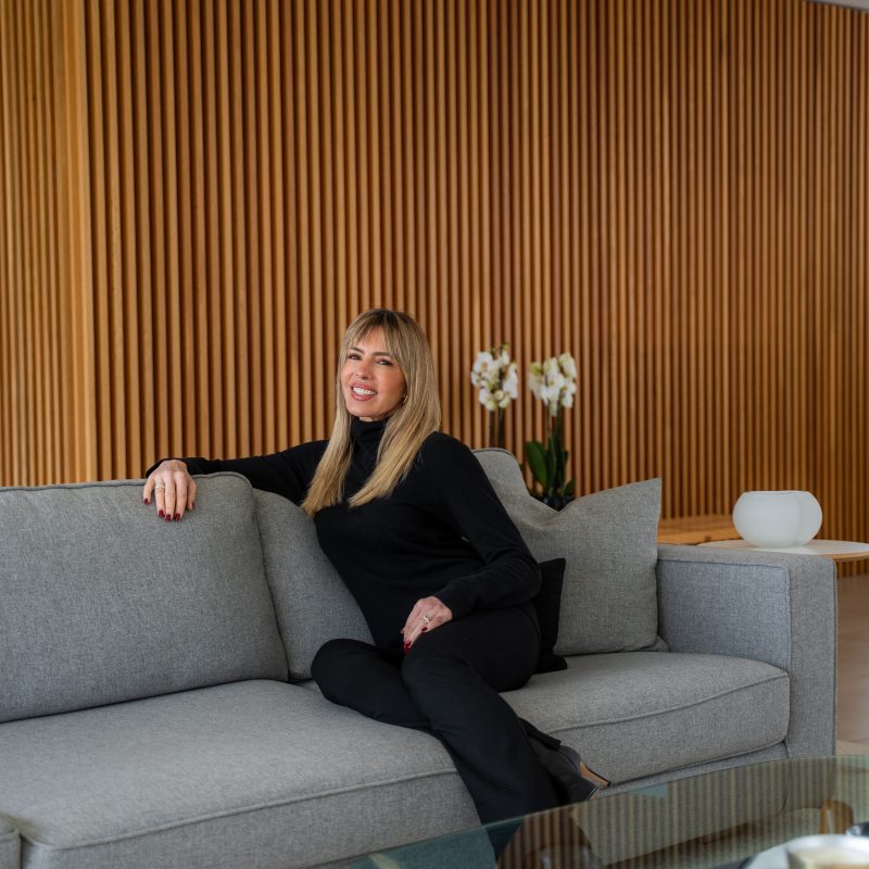 Esther Sarphatie smiling while seated on a gray couch.