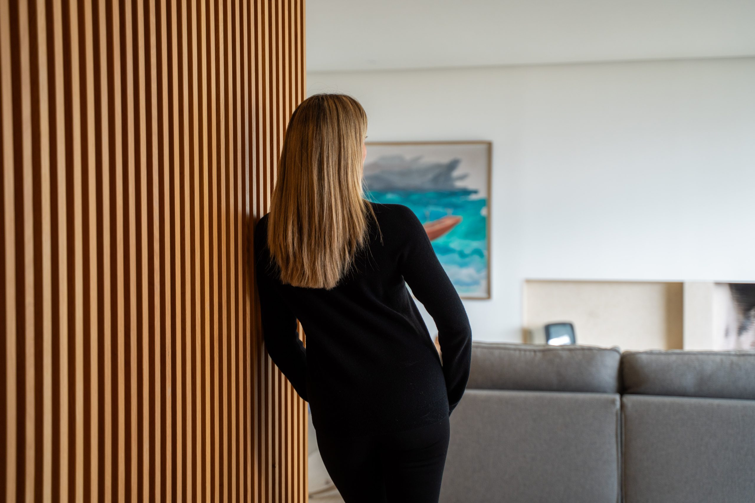 Back view of Esther Sarphatie standing beside a wooden slat wall.