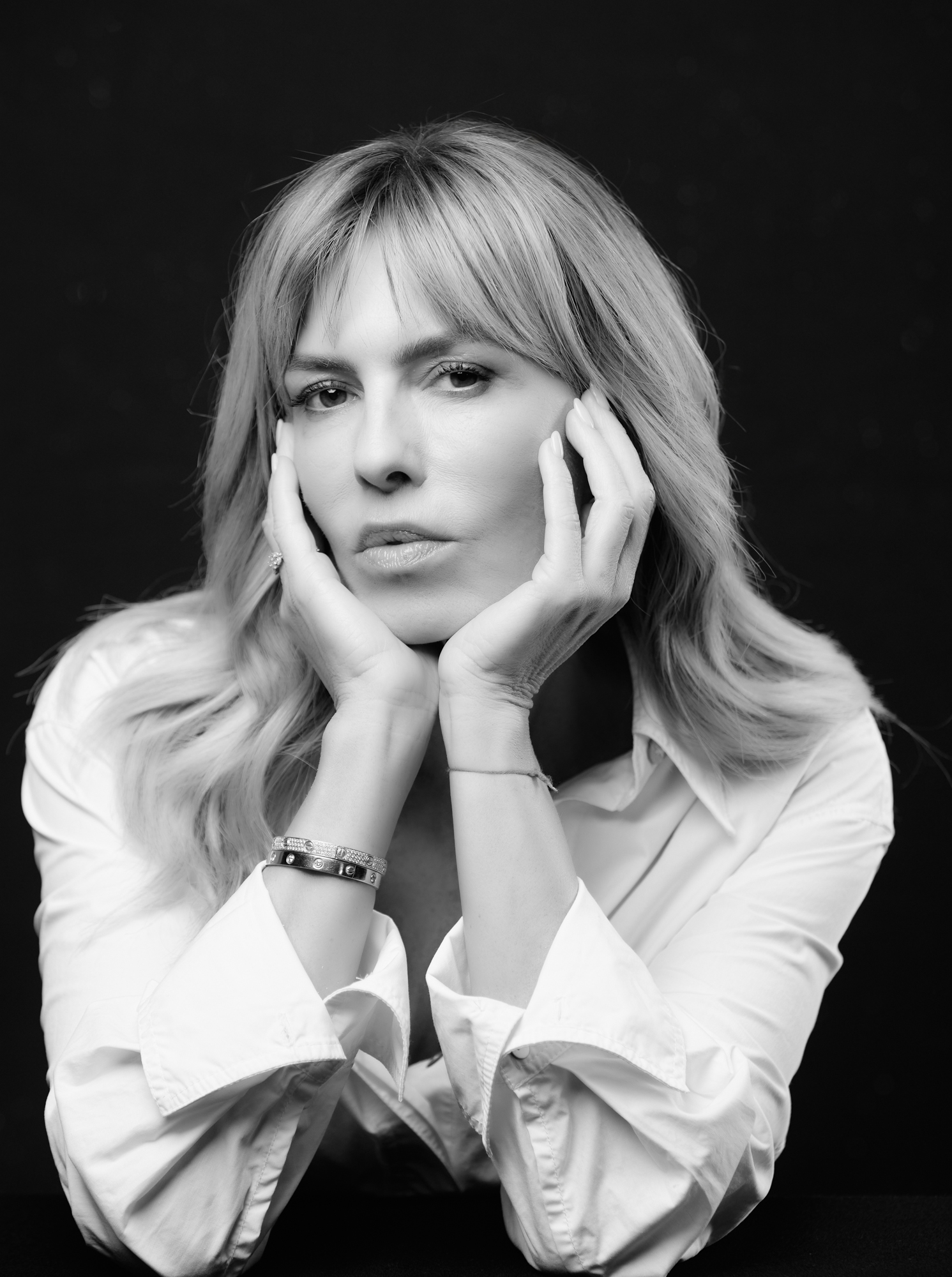 Esther Sarphatie in a black-and-white portrait, hands on cheeks, wearing a white shirt.