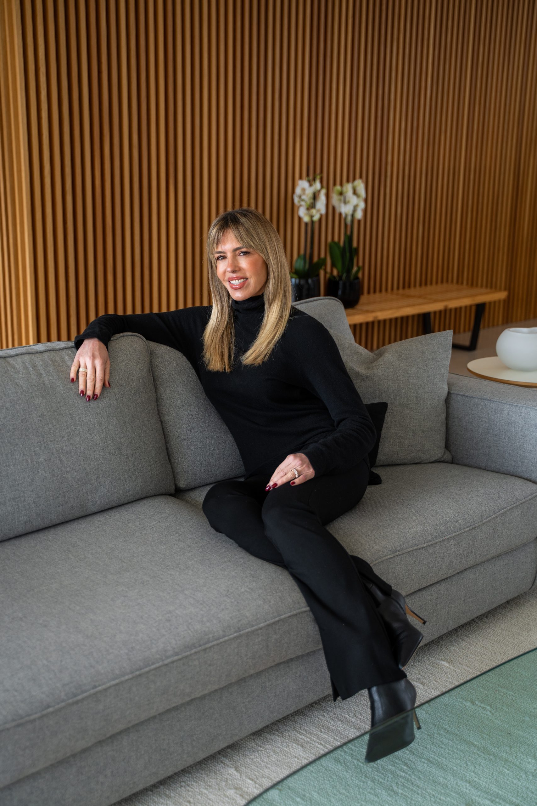 Esther Sarphatie smiling sitting on a gray couch.